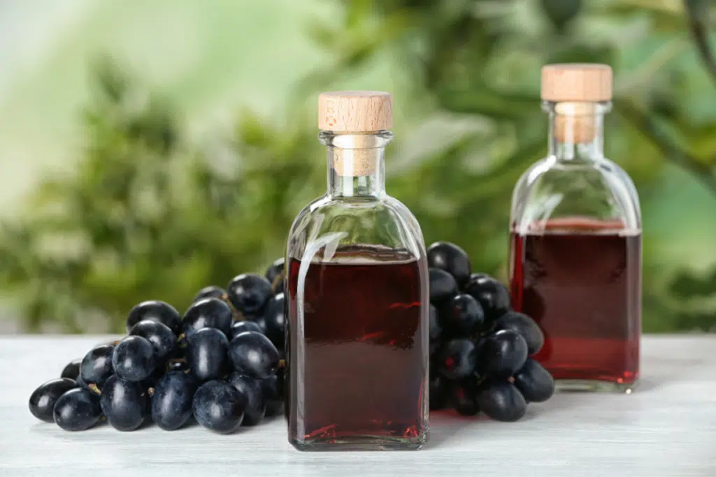 sticle cu otet de vin si struguri pe masa din lemn